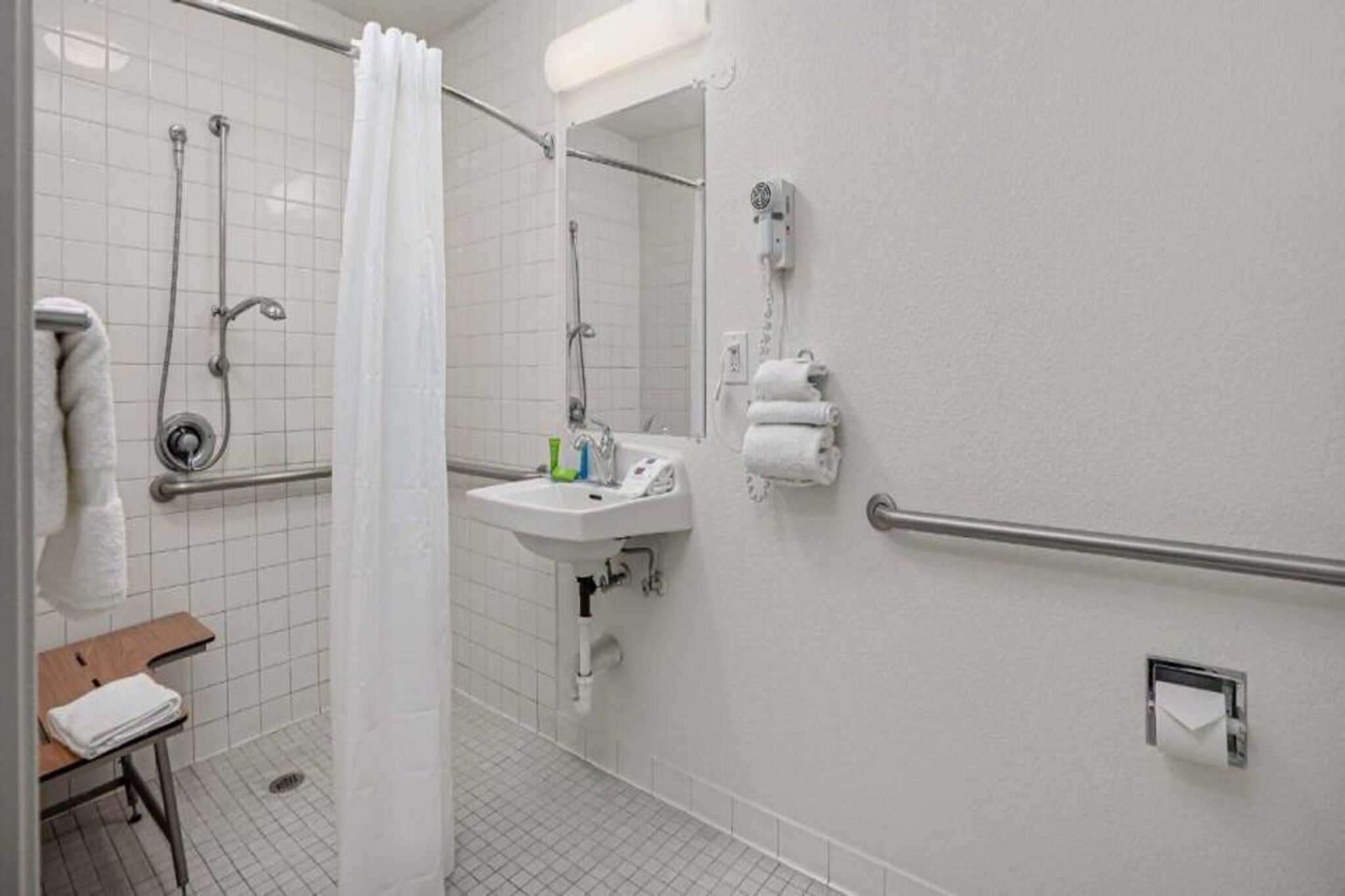 A bathroom with a shower, a sink, a toilet, and a hand dryer.