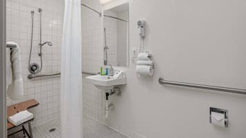 A bathroom with a shower, a sink, a toilet, and a hand dryer.