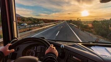 A driver's perspective inside a vehicle on a highway with a clear sky and distant mountains.