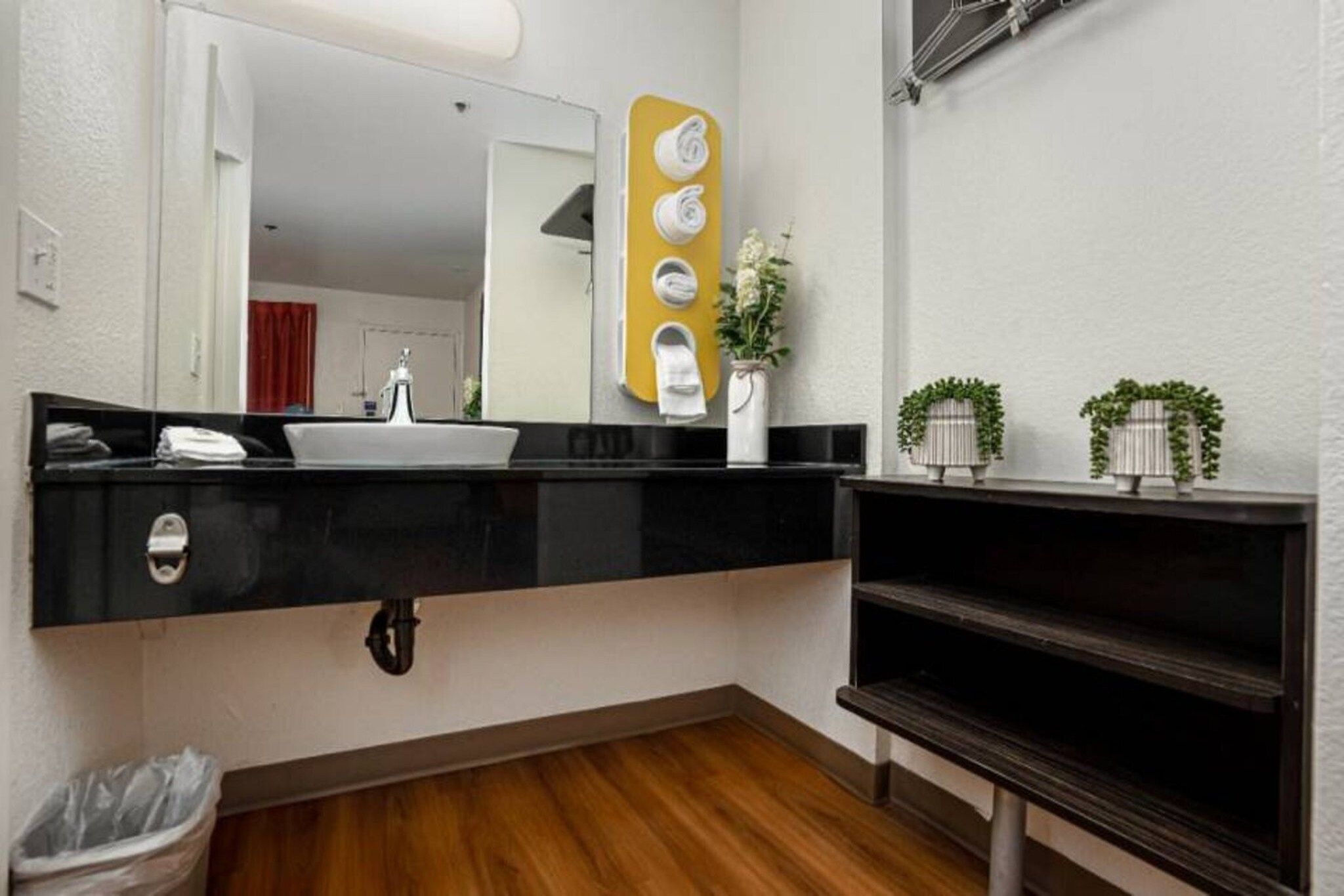A bathroom with a black countertop, a white sink, a mirror, and a towel rack.