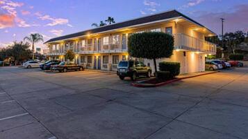 A motel with multiple rooms, a parking lot, and a small tree in front.