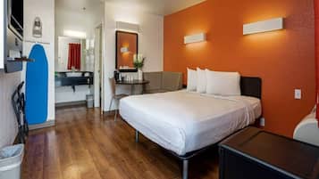 A hotel room with a bed, a desk, and a chair.