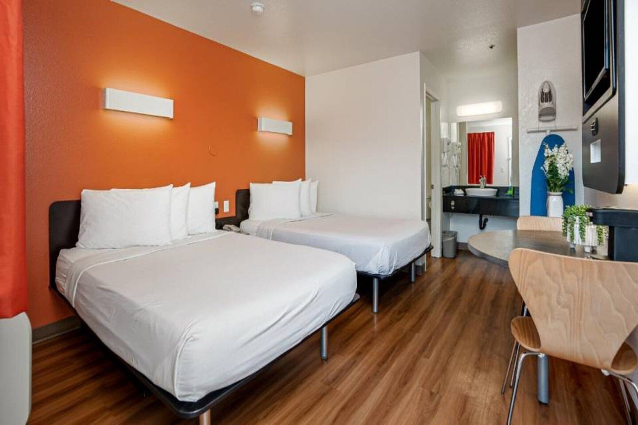 A hotel room with two beds, a desk, and a chair.