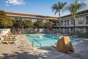 A hotel pool area with lounge chairs, a covered pool, and a building with balconies. - 2 Full Beds | Premium, Mini Fridge (Temecula)