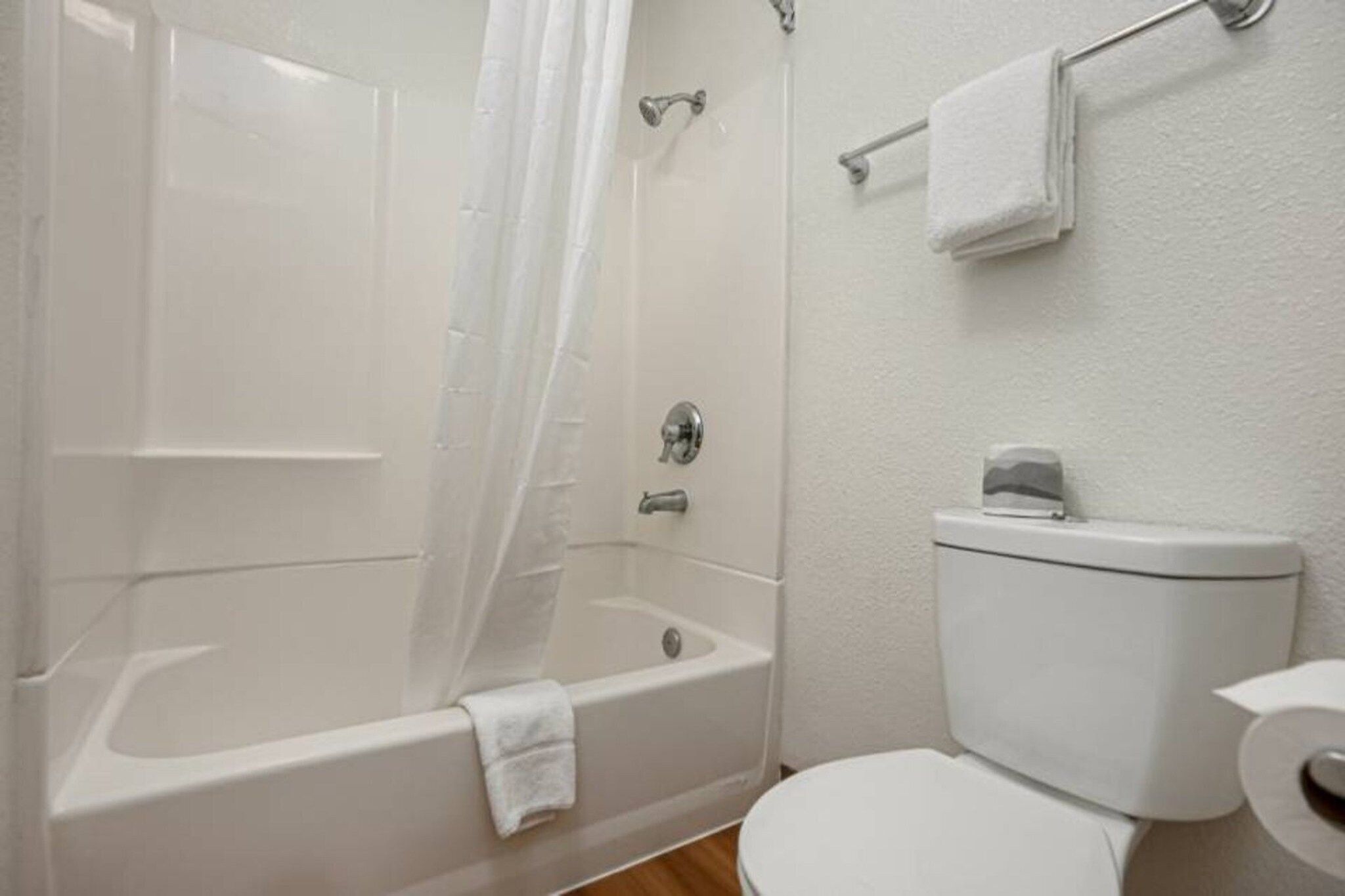 A bathroom with a bathtub, toilet, and a shower curtain.