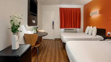 Een hotelkamer met een bed, een bureau, een stoel, een televisie en een raam met gordijnen.