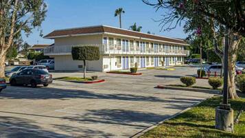 A motel with a central parking lot, a small tree, and a clear sky.