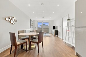 A modern dining area with a round table and chairs, a white cabinet, and a view through a glass door. - 2 Bed 2 Bath Willesden Junction New furniture (Greater London)