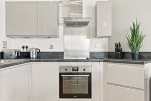 A modern kitchen with stainless steel appliances, a built-in oven, and a countertop with a coffee maker and toaster. - 2 Bed 2 Bath Willesden Junction New furniture (Greater London)