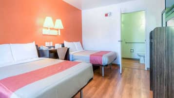 A hotel room with two beds, a desk, a chair, a lamp, and a wardrobe.