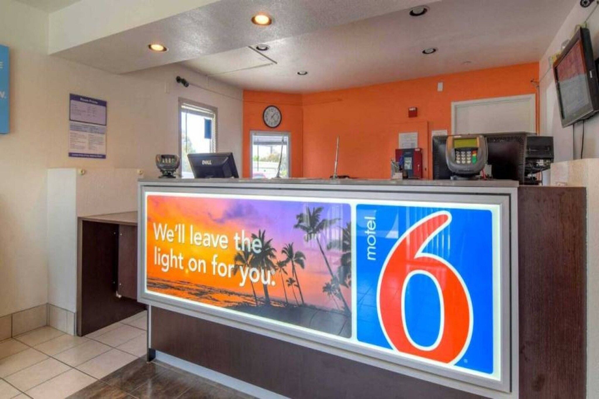 A hotel reception desk with a large sign reading 'We'll leave the light on for you.'