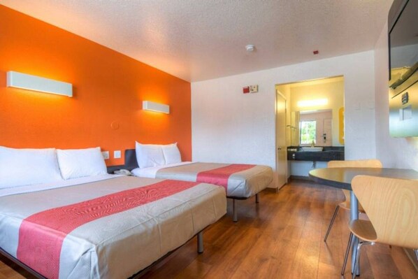 Una habitación de hotel con dos camas, una mesita pequeña y una silla.