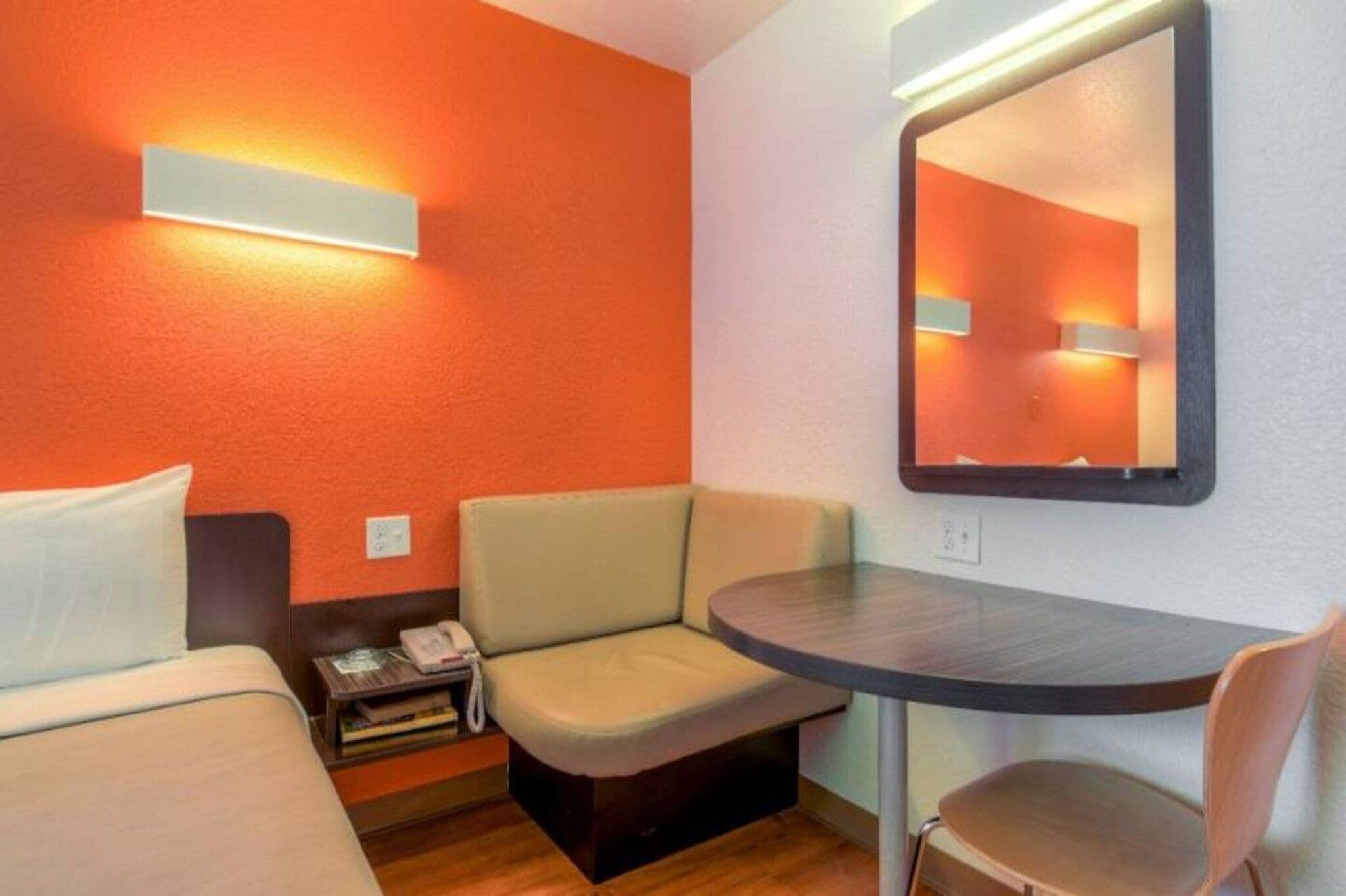 Ein Hotelzimmer mit einem Bett, einem kleinen Tisch, einem Sessel, einer Couch und einem Spiegel.