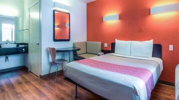 Ein Hotelzimmer mit Bett, Schreibtisch, Stuhl und Bad.
