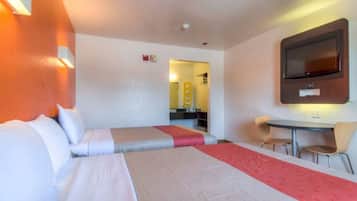 A hotel room with two beds, a TV, a small table, and a chair.