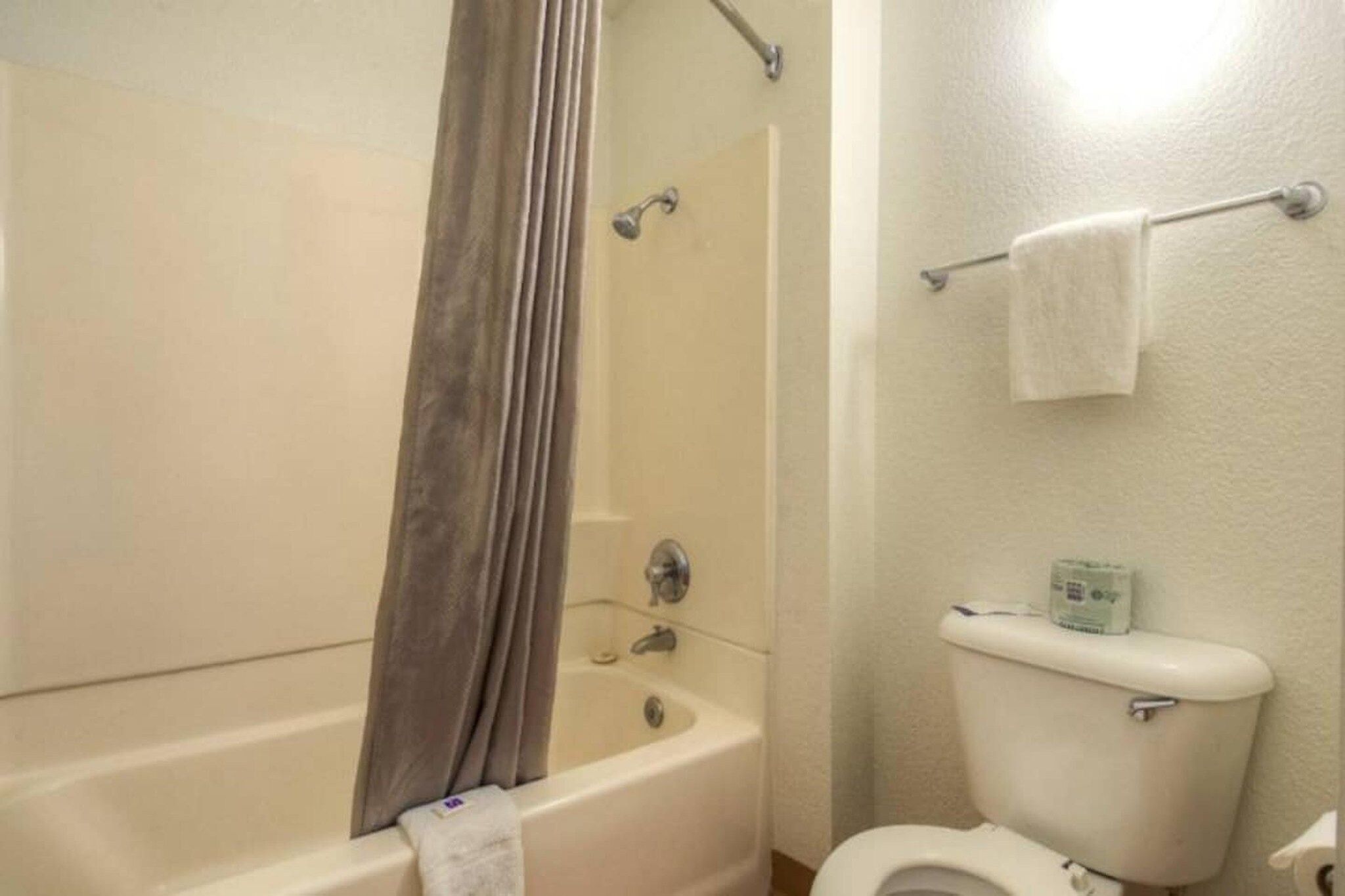 A bathroom with a bathtub, shower, toilet, and a towel rack.