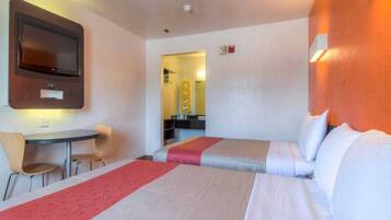 A hotel room with two beds, a desk, and a chair.