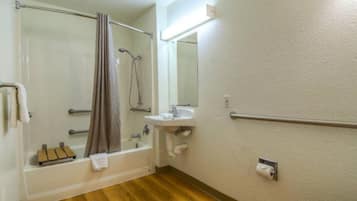 A bathroom with a bathtub, a sink, a mirror, a towel rack, and a toilet.