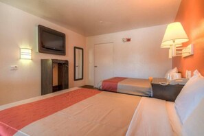 Een hotelkamer met twee bedden, een televisie, een deur en een wandlamp.