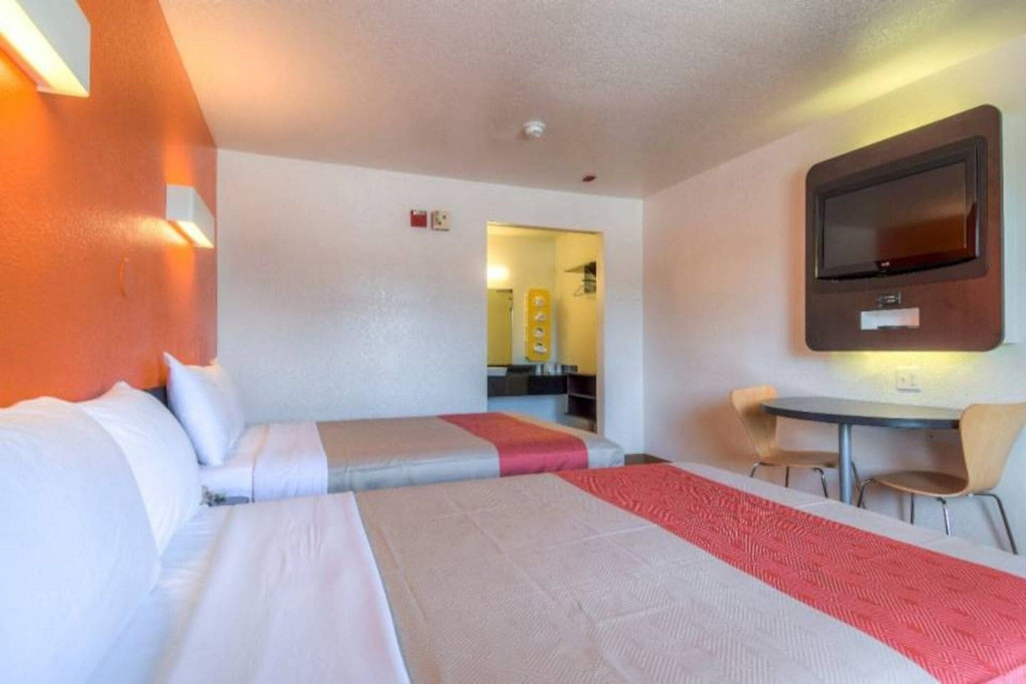 Ein Hotelzimmer mit zwei Betten, einem Fernseher, einem kleinen Tisch und einem Sessel.