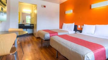 Una habitación de hotel con dos camas, una mesita y una silla.