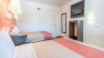 Habitación de hotel con dos camas, televisión, armario y mesita de noche con lámpara.