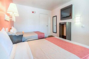 A hotel room with two beds, a television, a wardrobe, and a bedside table with a lamp. - 2 Full Beds | Mini Fridge (Chula Vista)
