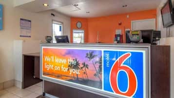 A hotel reception desk with a large sign reading 'We'll leave the light on for you.'
