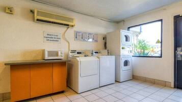 A laundry room with a microwave, washing machines, and a dryer.