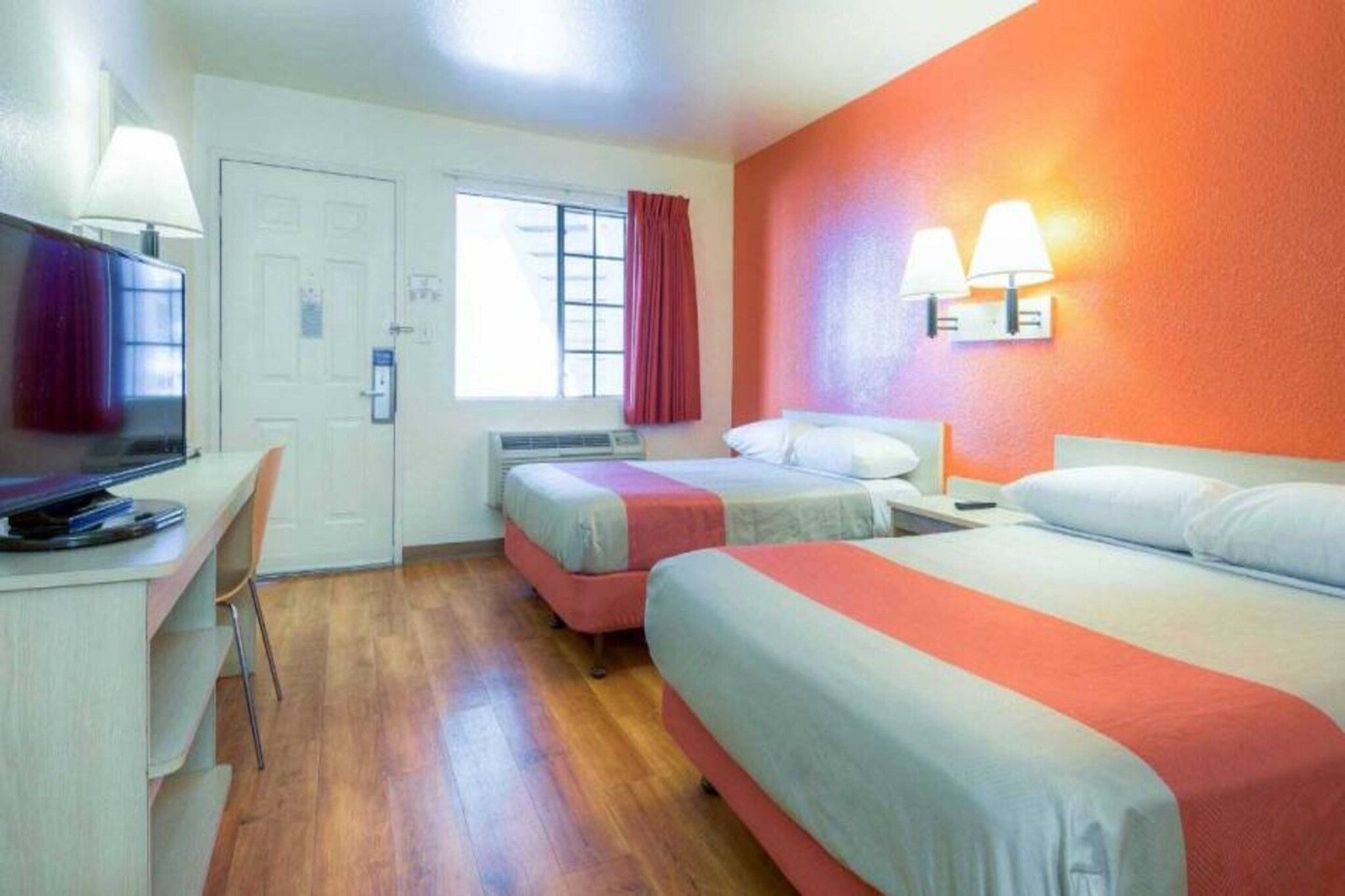 Une chambre d’hôtel avec deux lits, un bureau, une chaise et un téléviseur.