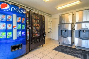 Un espace comprenant des distributeurs automatiques, notamment un distributeur de Pepsi et un présentoir réfrigéré, ainsi qu’un appareil distributeur d’eau.