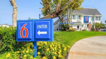 A motel sign with a number 6 and an arrow pointing left, indicating the direction to enter.