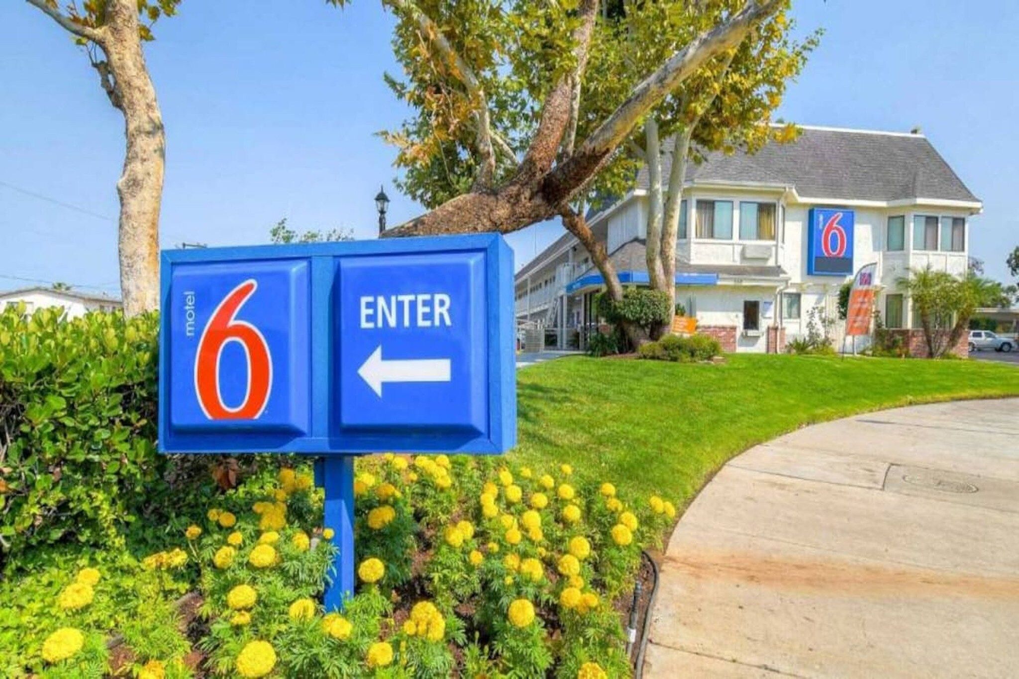 A motel sign with a number '6' and an arrow pointing left, indicating the direction to enter.