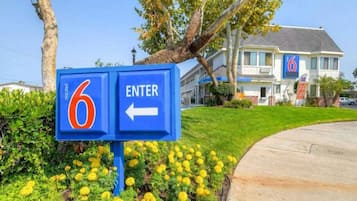 A motel sign with a number '6' and an arrow pointing left, indicating the direction to enter.