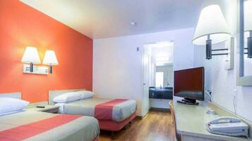 A hotel room with two beds, a desk, a chair, a television, and a telephone.