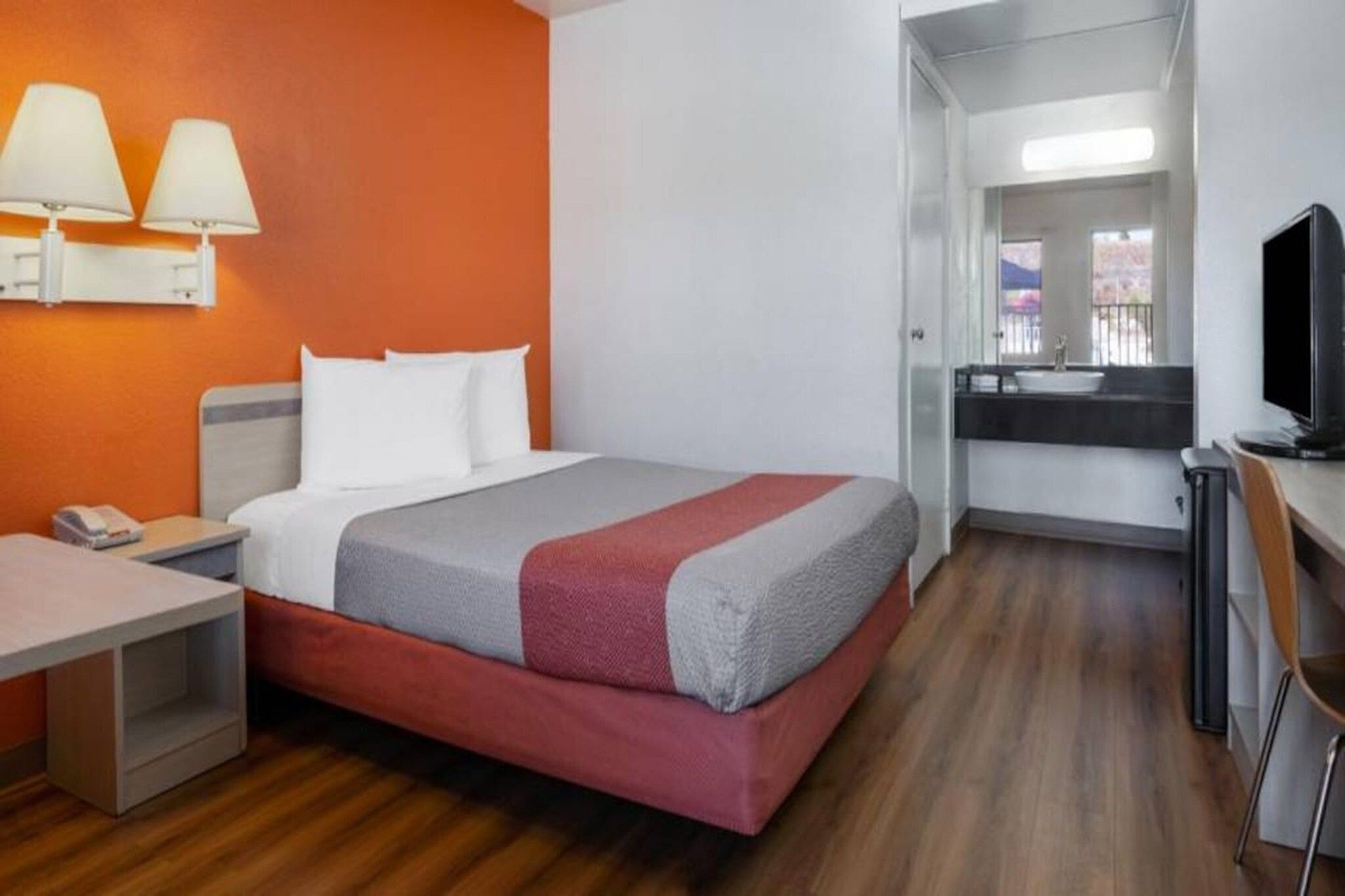 Une chambre d’hôtel avec un lit, une table de chevet, une lampe et une vue sur l’extérieur.