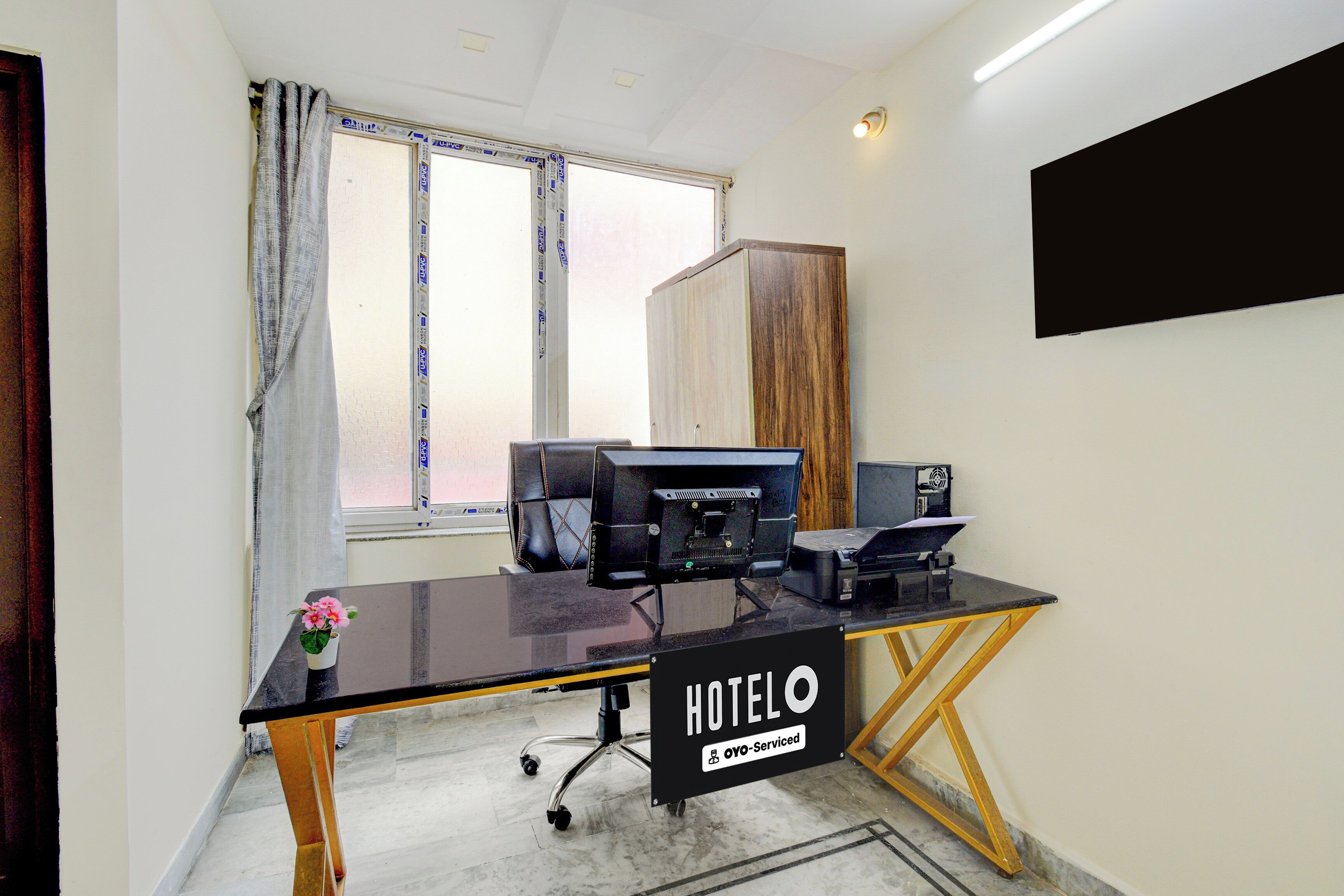 Una habitación de hotel con escritorio, computadora y televisor instalado en la pared.