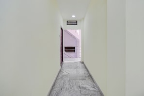 Un couloir au sol en marbre menant à un escalier.