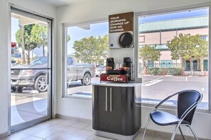 A coffee station with a sign offering a morning charge-up for no charge, a coffee machine, and a chair. - Spacious 1  Queen Bed|Free Parking (Campbell)