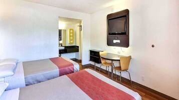 A hotel room with two beds, a desk, a chair, and a television.