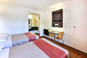 Une chambre d’hôtel avec deux lits, un bureau, une chaise et un téléviseur.