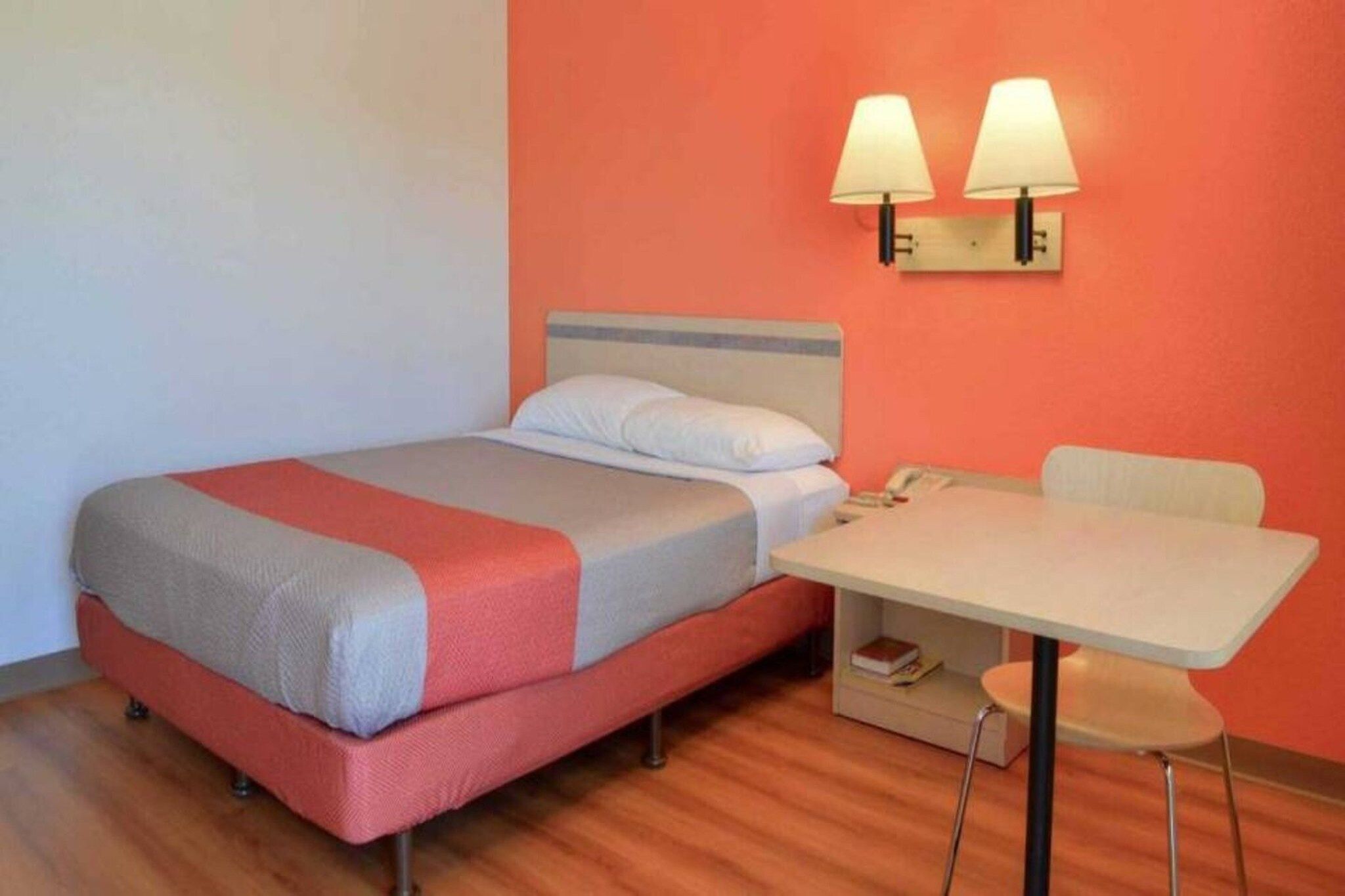 A single bed with a headboard, a bedside table with a lamp, and a chair.