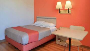 A single bed with a headboard, a bedside table with a lamp, and a chair.