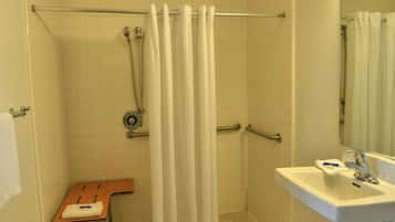 A bathroom with a shower, a sink, and a wooden chair.