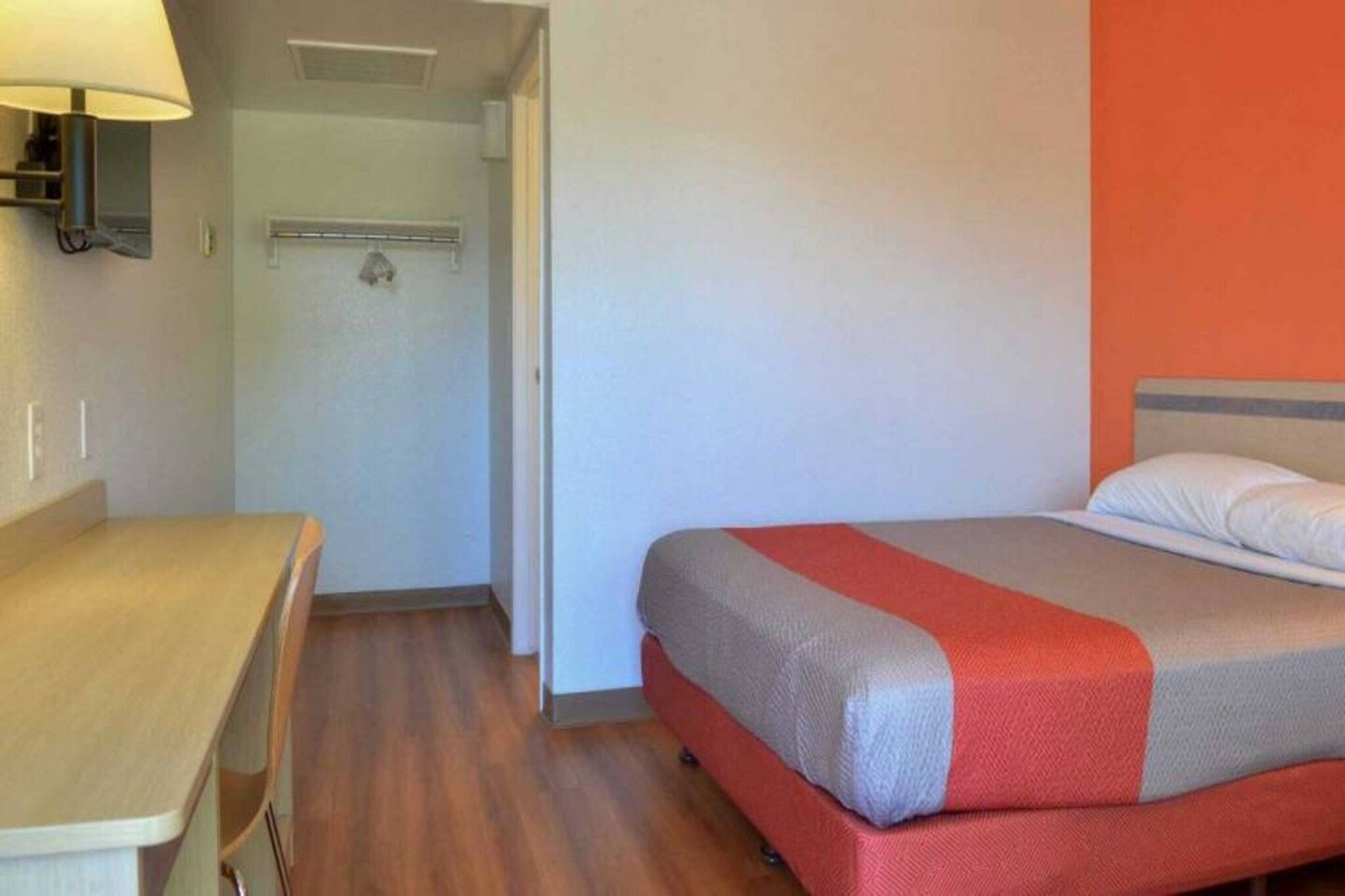 Una habitación de hotel con cama, escritorio y lámpara.