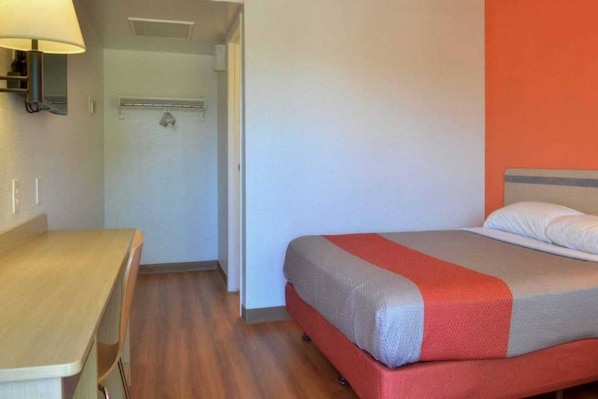 A hotel room with a bed, a desk, and a lamp.