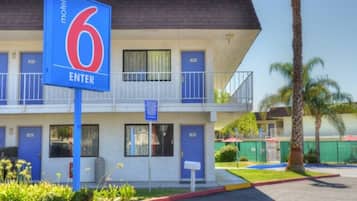 Ein Motel mit einem auffälligen, blauen Schild mit der Aufschrift '6 ENTER', mehreren blauen Türen und einem Balkon im zweiten Stock.