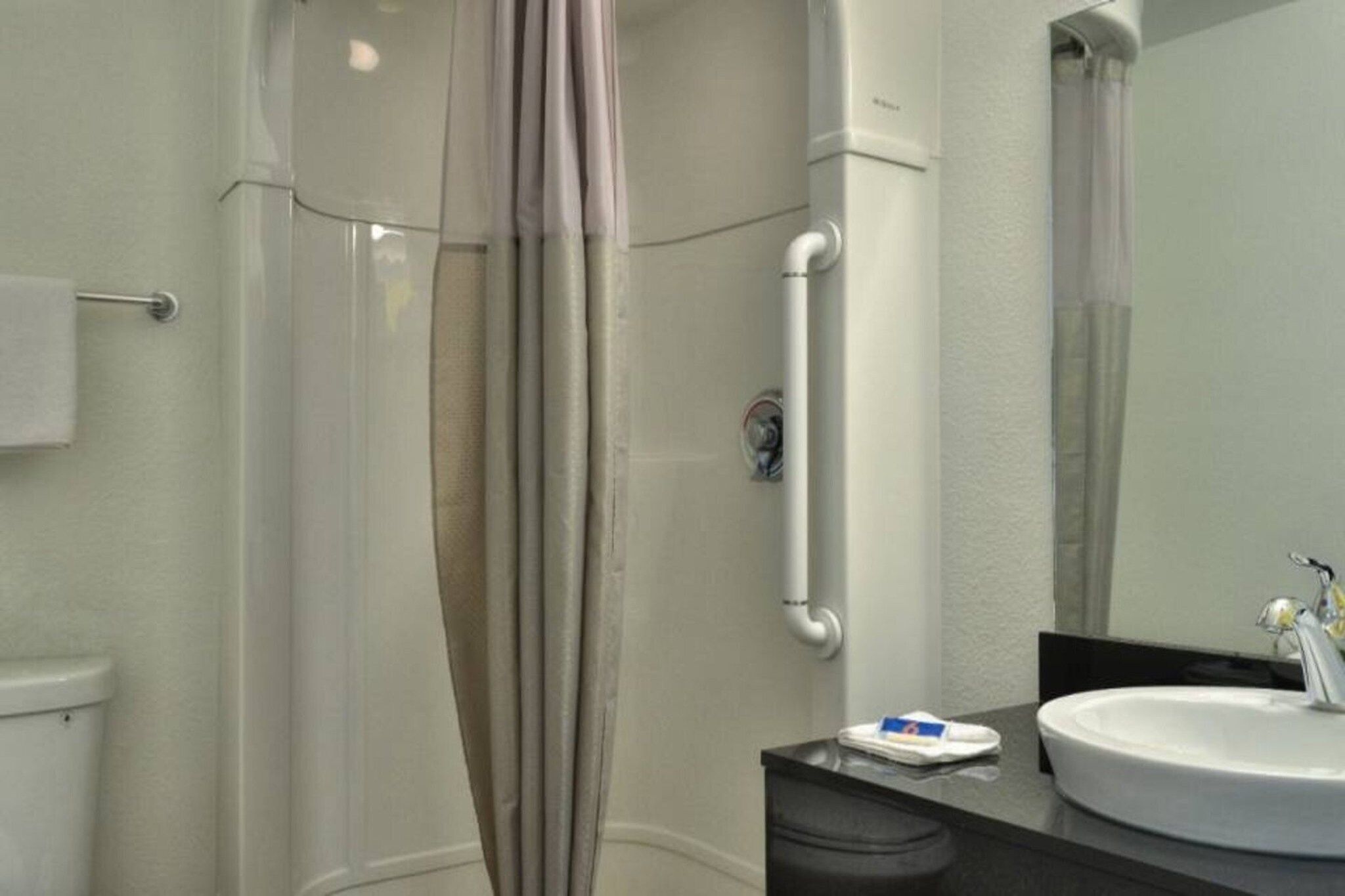 Ein Badezimmer mit Toilette, Waschbecken, Spiegel und Duschkabine.