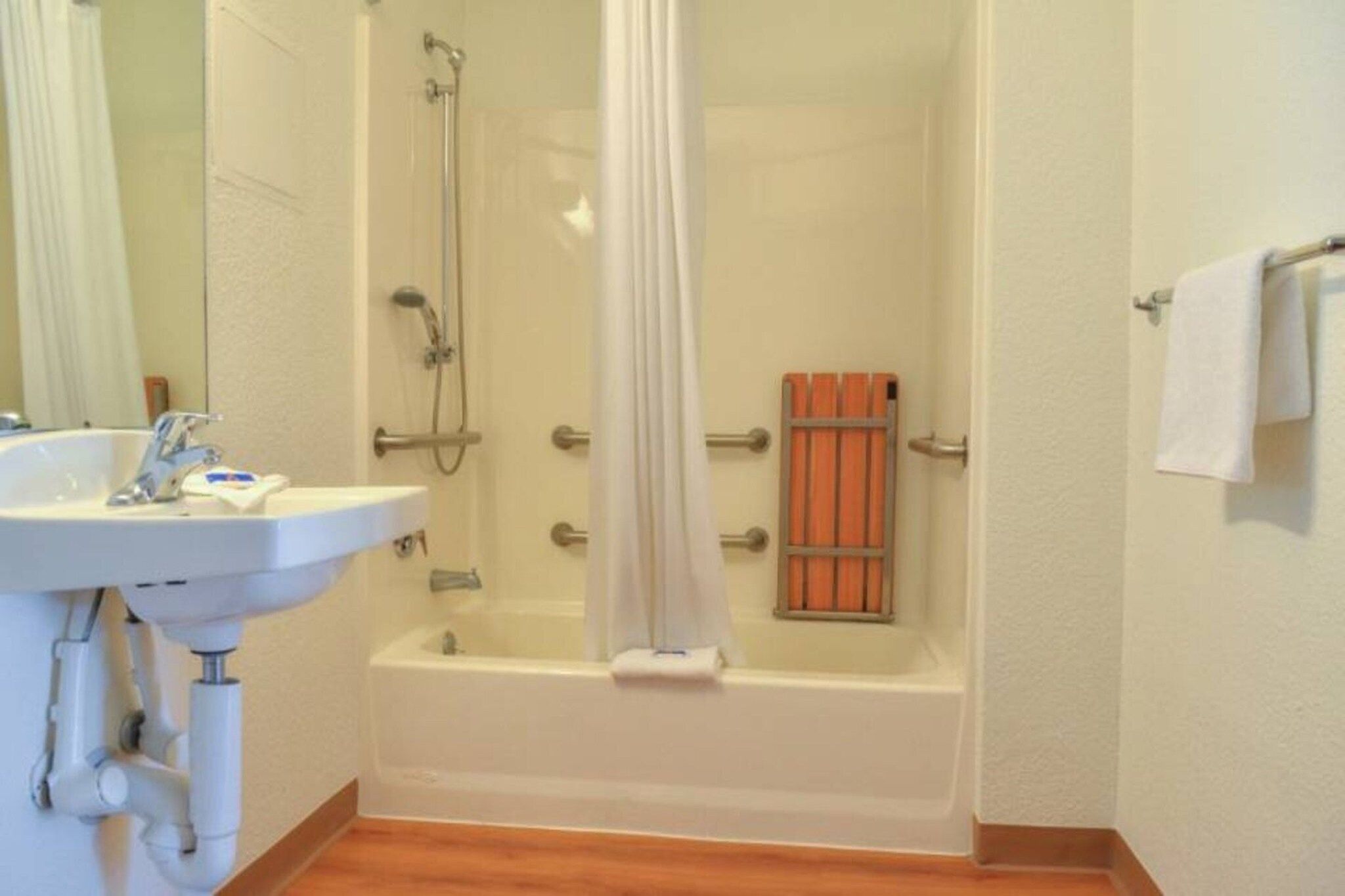 A bathroom with a bathtub, a shower, a sink, and a towel rack.