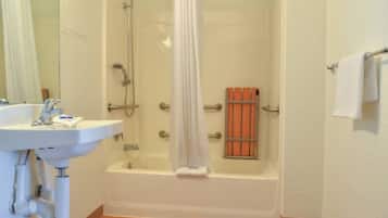 A bathroom with a bathtub, a shower, a sink, and a towel rack.